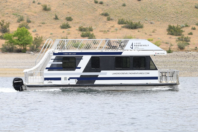 Lake Roosevelt houseboat passing by a dry hillside on the water.