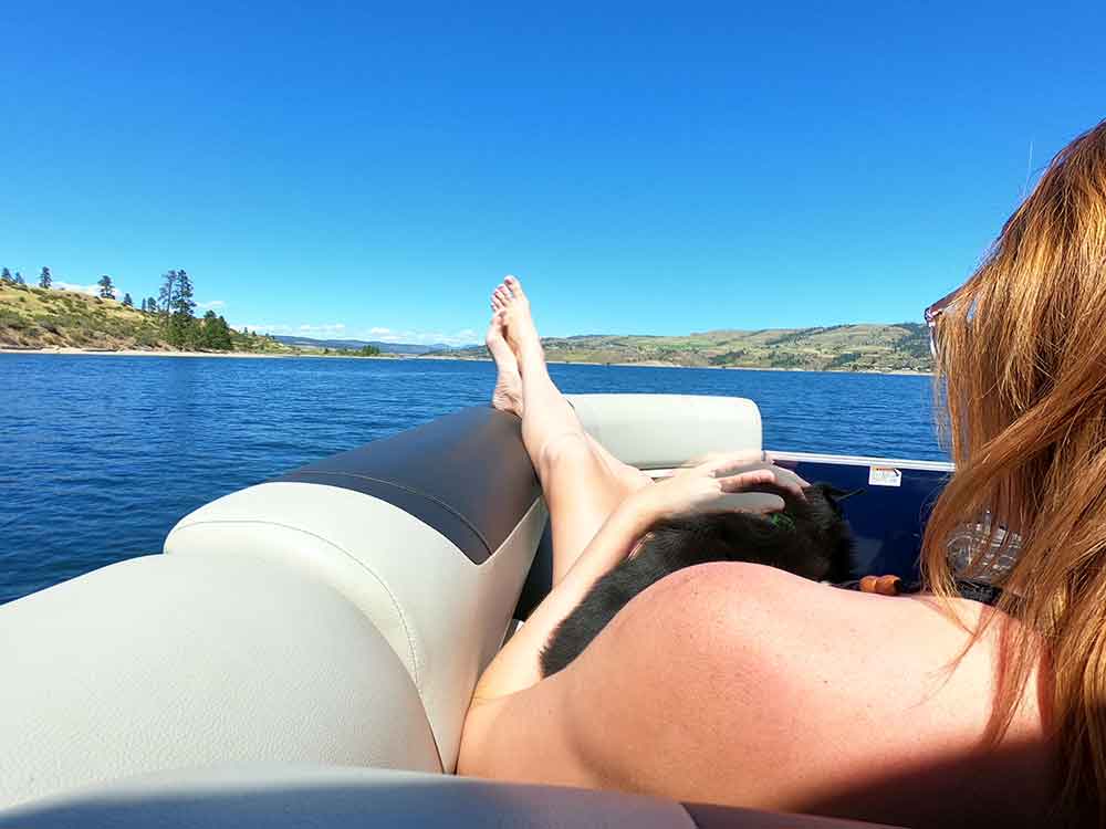 A woman relaxing on a pontoon boat with her feet up on the lake.