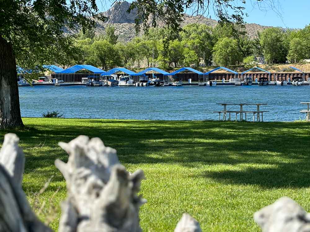 Blue-roofed marina docks across the lake with grassy shoreline in front.