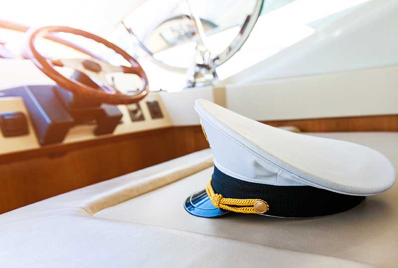 Captain’s hat resting on a boat seat near the steering wheel.