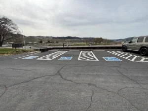 Three accessible parking spaces with striped access aisles overlooking a waterfront area.