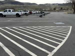 White-striped access aisle next to an accessible parking space in a large parking lot.