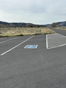 Accessible parking space beside a striped no-parking zone in an empty asphalt lot.