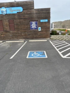 Accessible parking space outside a wooden building with a striped access aisle beside it.